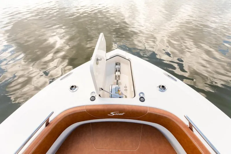 Slide: The Image of 2023 Scout 277 LXF boat bow with anchor compartment open on calm water. - 8
