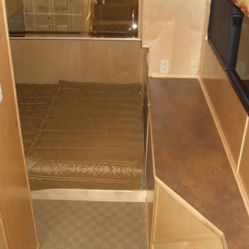 Slide: The Image of Interior of 2007 Stardust Cruisers Sundancer, featuring a cozy bed and wooden cabinetry. - 3