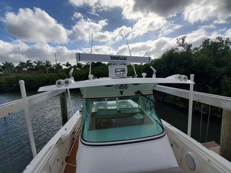 Slide: The Image of 2008 Everglades 350 CC boat docked near lush greenery under a partly cloudy sky. - 27