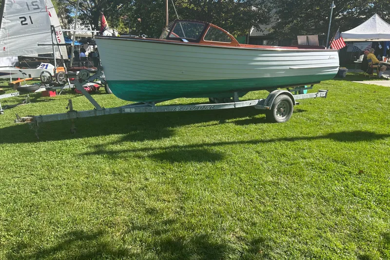 The Image of 1957 Lyman Islander boat on trailer, displayed outdoors on grass. - 0