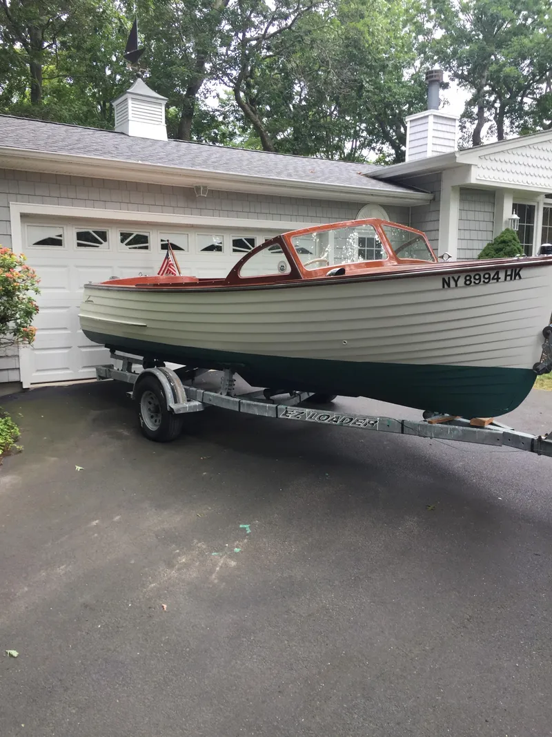 Slide: The Image of 1957 Lyman Islander boat on a trailer in front of a garage. - 2
