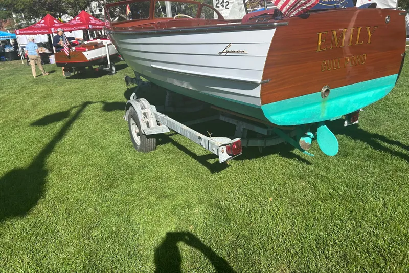 Slide: The Image of 1957 Lyman Islander boat named "Emily" on trailer, displayed outdoors on grass. - 22