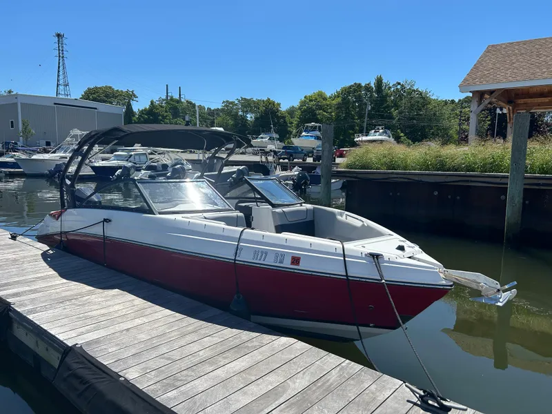 Slide: The Image of 2019 Rinker Q5 OB boat docked at a marina under clear blue skies. - 0
