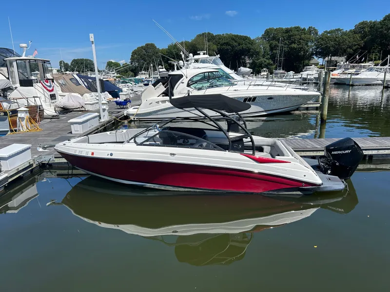 Slide: The Image of 2019 Rinker Q5 OB boat docked at a marina with other vessels. - 1