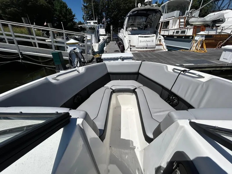 Slide: The Image of 2019 Rinker Q5 OB boat interior with gray seating, docked at a marina. - 13