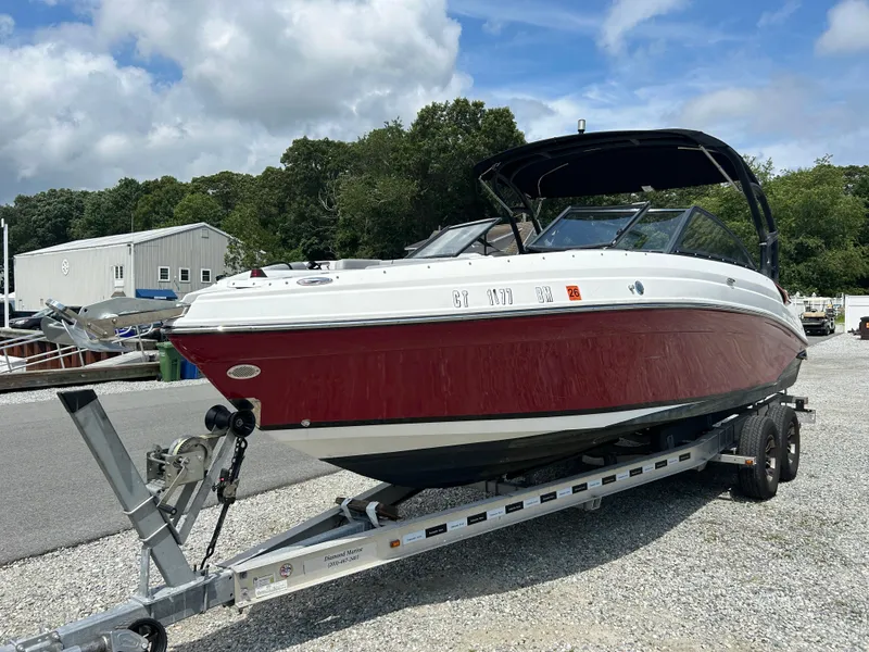 Slide: The Image of 2019 Rinker Q5 OB boat on trailer, red and white, parked outdoors. - 7