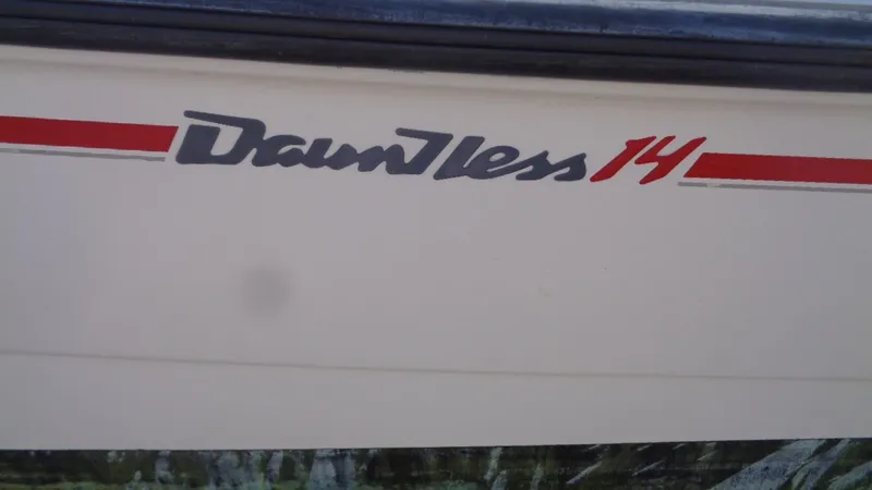Slide: The Image of 1999 Boston Whaler 140 Dauntless boat logo with red and gray text on white hull. - 13
