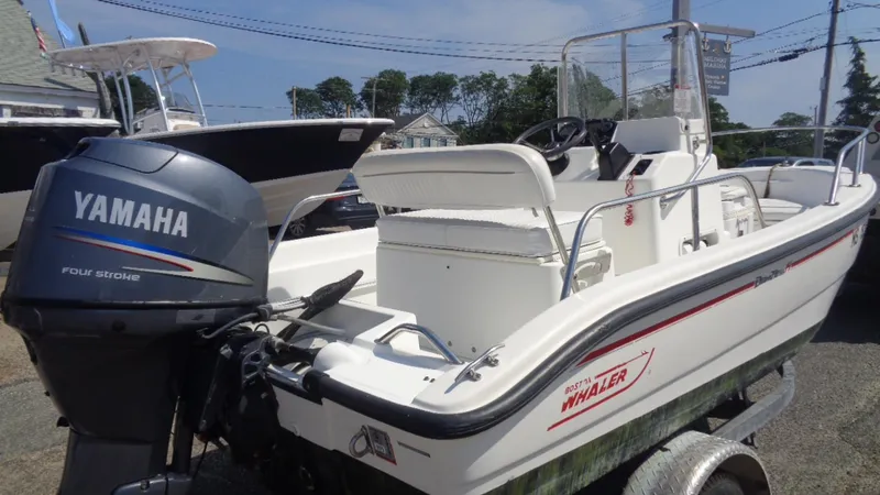 Slide: The Image of 1999 Boston Whaler 140 Dauntless boat with Yamaha outboard motor, parked on a trailer. - 5