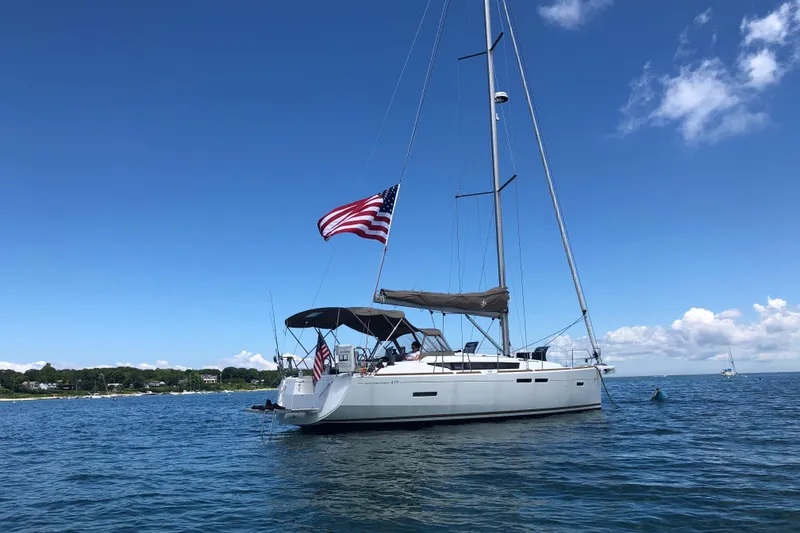 The Image of 2018 Jeanneau Sun Odyssey 419 sailboat on calm water, American flag waving. - 0