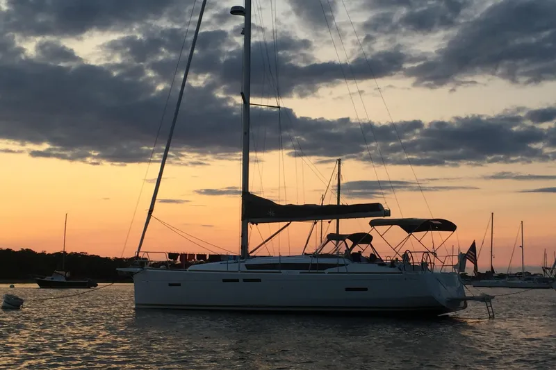 Slide: The Image of 2018 Jeanneau Sun Odyssey 419 sailboat at sunset, anchored in a tranquil harbor. - 2