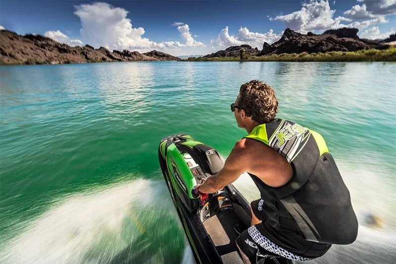 Slide: The Image of Man riding 2023 Kawasaki SX-R jet ski on a scenic lake. - 4