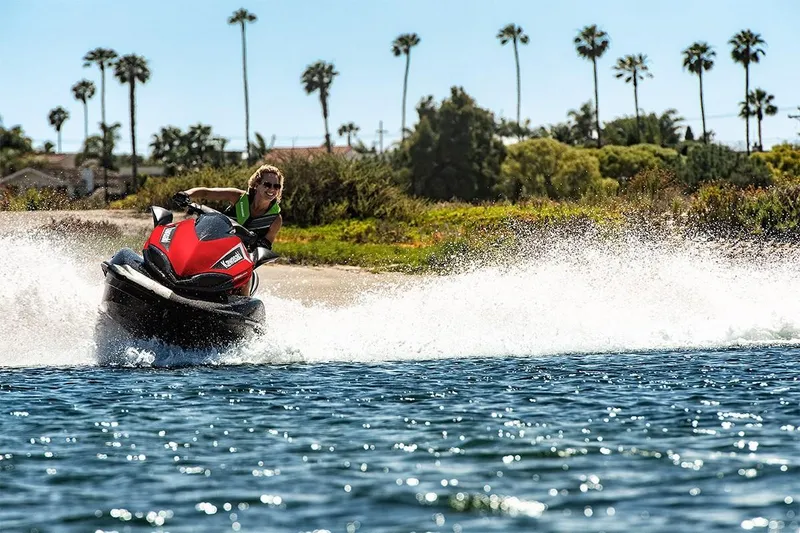 Slide: The Image of 2023 Kawasaki Ultra 310 jet ski speeding on water near a scenic shoreline. - 3