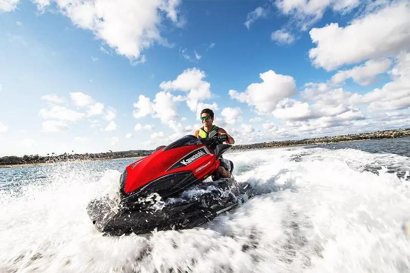 Slide: The Image of 2023 Kawasaki Ultra 310 jet ski speeding on water under a blue sky with clouds. - 4