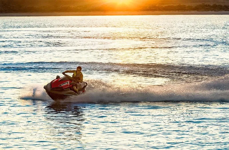 Slide: The Image of Person riding a 2023 Kawasaki Ultra 310 jet ski at sunset on a lake. - 5