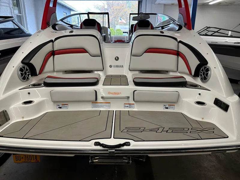 Slide: The Image of 2020 Yamaha Boats 242X, rear view, showcasing seating and deck design in a showroom. - 8