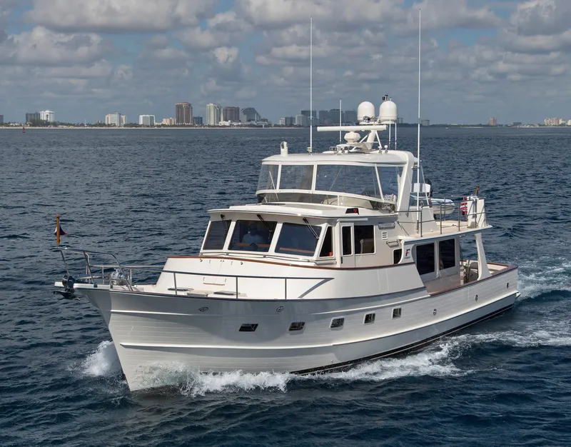 Slide: The Image of Luxury Fleming 55 yacht cruising on open water, 2027 model, city skyline in background. - 2