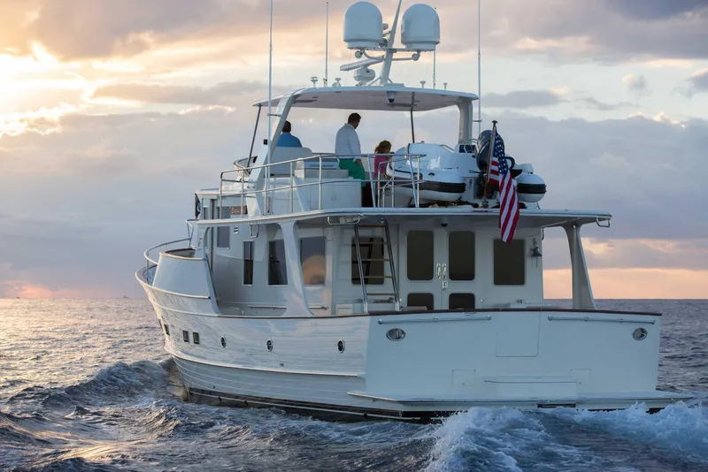 Slide: The Image of Luxury Fleming 58 yacht cruising at sunset, 2027 model, with people on deck. - 2