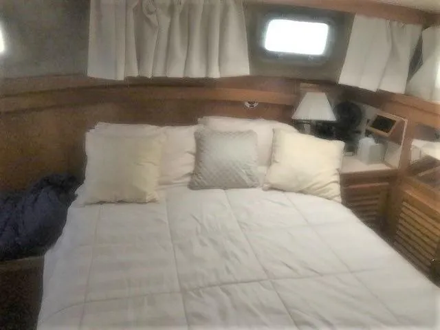 Slide: The Image of 1986 Silverton 40 Double Cabin bedroom with cozy bed, pillows, and porthole windows. - 13