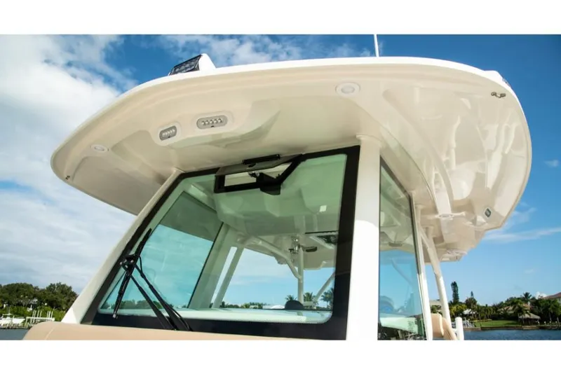 Slide: The Image of 2023 Sailfish 360 CC boat, close-up of the helm and hardtop under blue sky. - 15