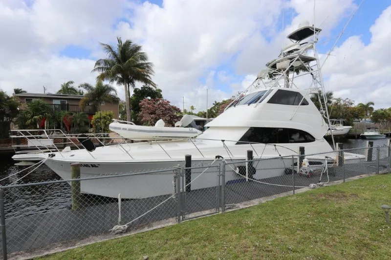 The Image of 2004 Riviera 58 Enclosed Flybridge yacht docked by a canal with palm trees. - 1