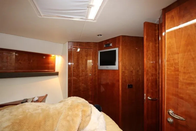 Slide: The Image of Luxurious bedroom interior of 2004 Riviera 58 Enclosed Flybridge yacht with TV and wooden cabinetry. - 14