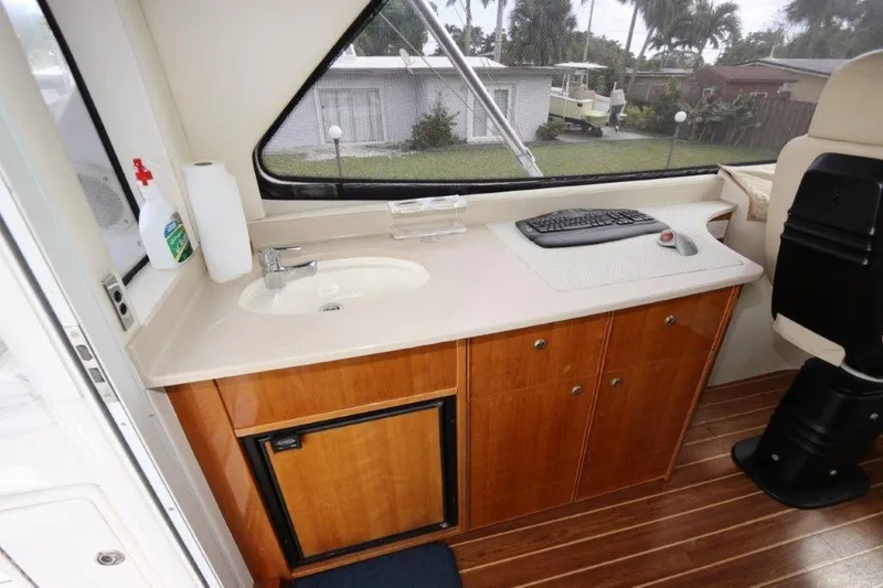 Slide: The Image of Interior of 2004 Riviera 58 Enclosed Flybridge with sink, counter, and storage cabinets. - 27