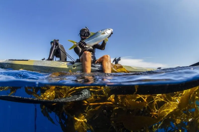 Slide: The Image of Person fishing from a 2023 Hobie Outback kayak, holding a fish above water. - 3
