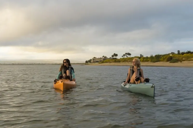 Slide: The Image of Two people kayaking on Hobie Revolution 11 kayaks, 2023 model, in calm waters near a shoreline. - 3