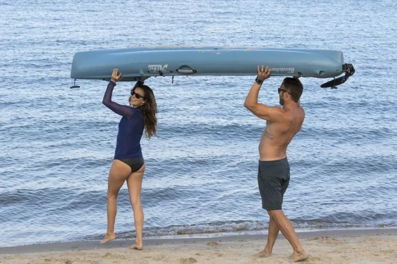 Slide: The Image of Couple carrying 2023 Hobie Revolution 11 kayak on a beach. - 5