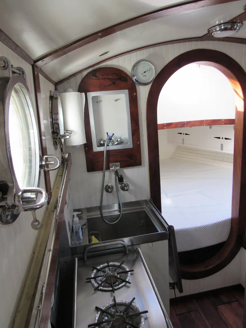Slide: The Image of 2009 Custom Pilothouse Cutter interior with compact kitchen and cozy sleeping area. - 21