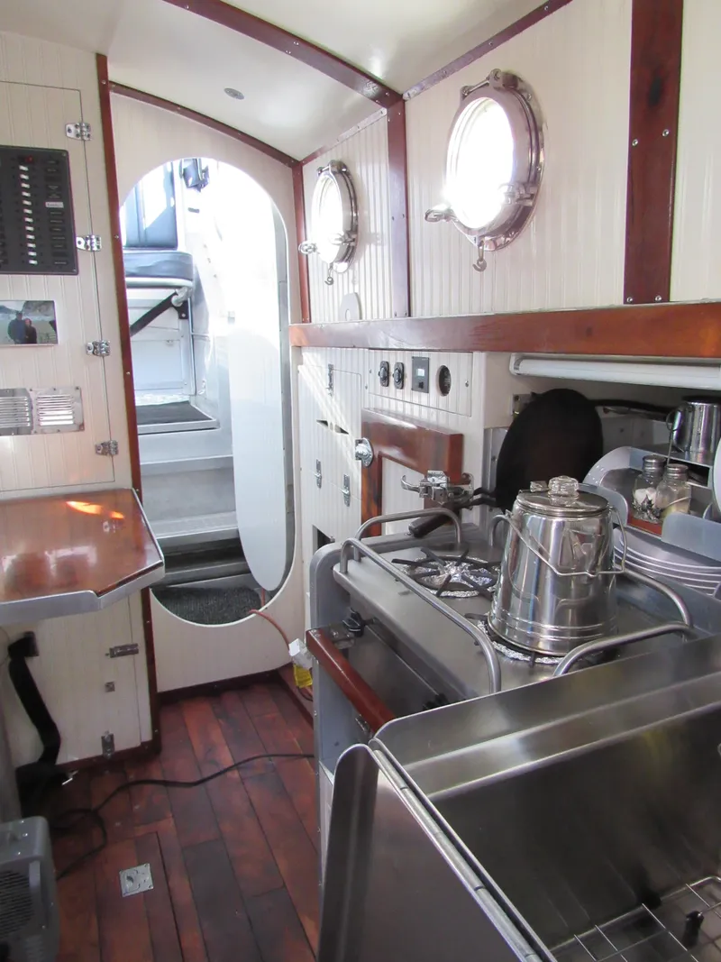 Slide: The Image of Interior of 2009 Custom Pilothouse Cutter with wooden flooring and compact kitchen area. - 27
