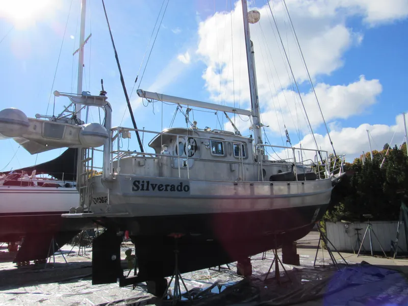 Slide: The Image of 2009 Custom Pilothouse Cutter sailboat on dry dock under a bright blue sky. - 44
