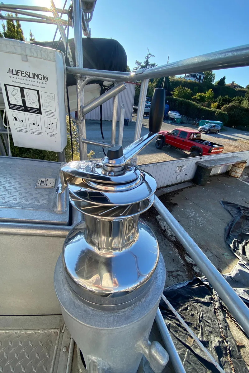 Slide: The Image of Stainless steel winch on 2009 Custom Pilothouse Cutter, docked with vehicles in background. - 48