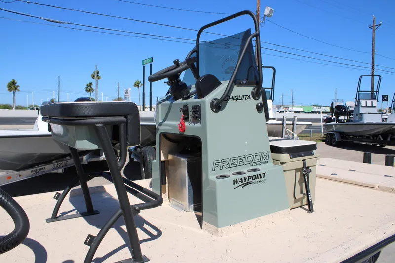 Slide: The Image of 2026 Freedom 14 Chiquita boat console with seating, parked outdoors under clear blue sky. - 10