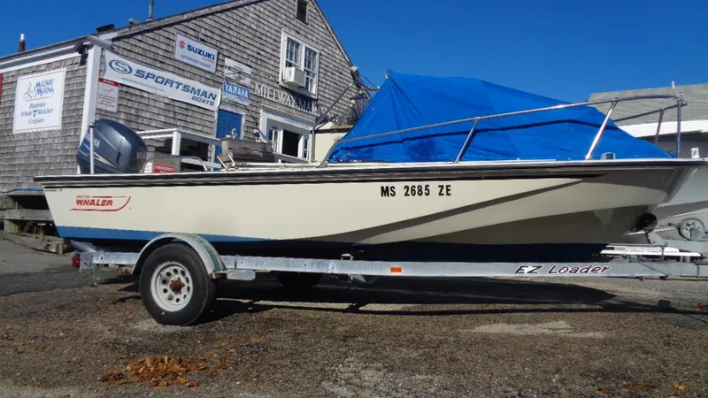 Slide: The Image of 1987 Boston Whaler 18 Outrage boat on trailer, parked outside a building. - 1