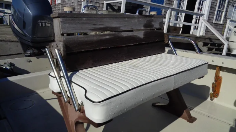 Slide: The Image of 1987 Boston Whaler 18 Outrage boat seat with white cushion and wooden backrest. - 4