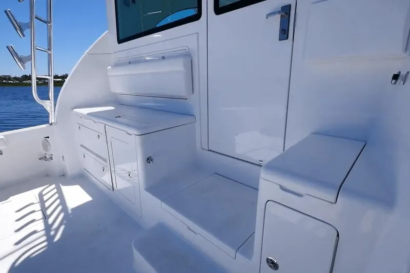 Slide: The Image of 2026 Henriques 50 EXHT boat interior with white cabinetry and seating, docked by the water. - 6