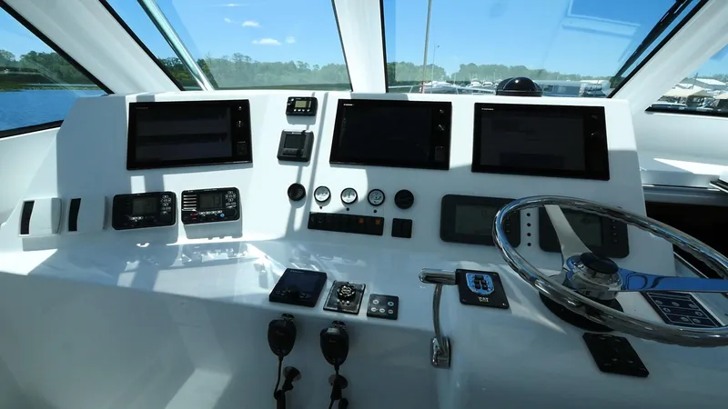Slide: The Image of Control panel of a 2025 Henriques 50 EXHT boat with multiple screens and steering wheel. - 8