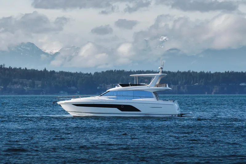 Slide: The Image of 2024 Prestige 590 yacht cruising on a scenic lake with mountains in the background. - 4