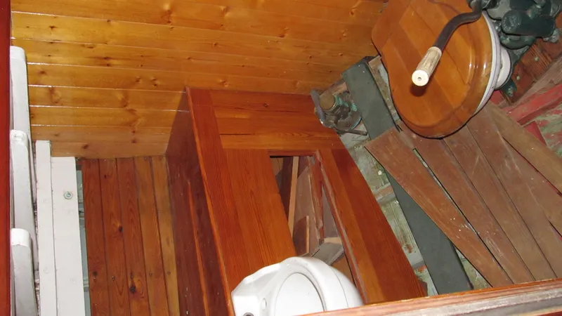 Slide: The Image of Wooden interior of a 1951 Concordia Yawl boat, featuring a compact bathroom area. - 6