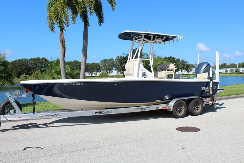 Slide: The Image of 2017 Pathfinder 2500 Hybrid boat on trailer, parked near palm trees and lake. - 2