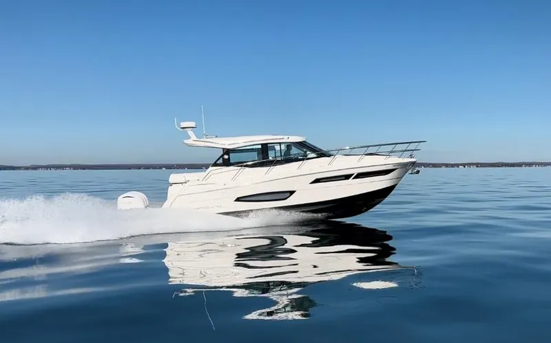 The Image of 2024 Regal 38XO yacht cruising on calm waters under clear blue sky. - 0
