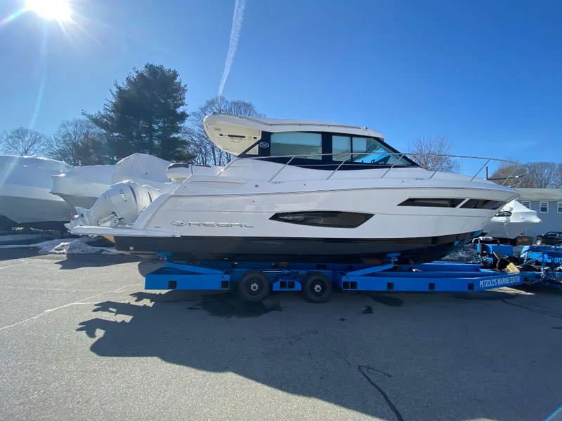 Slide: The Image of 2024 Regal 38XO boat on a blue trailer under clear sky. - 25