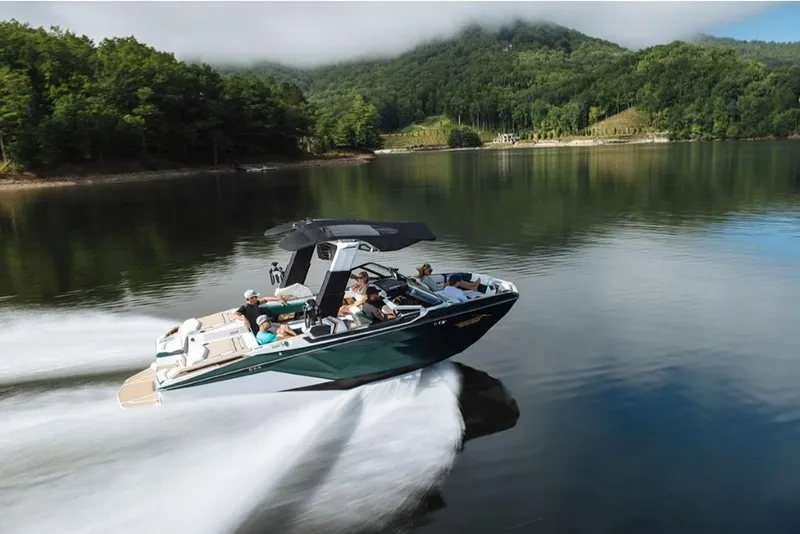 Slide: The Image of 2023 Nautique Super Air Nautique G23 Paragon cruising on a serene lake with lush green hills. - 19
