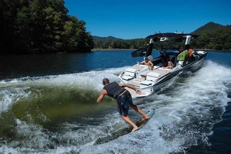 Slide: The Image of 2023 Nautique Super Air Nautique G23 Paragon towing a wakeboarder on a scenic lake. - 23