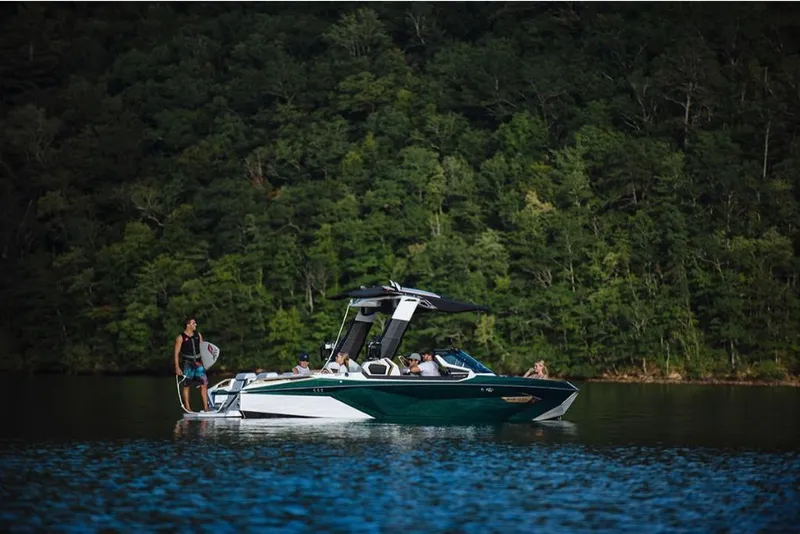 Slide: The Image of 2023 Nautique Super Air Nautique G23 Paragon on a serene lake with lush forest backdrop. - 4