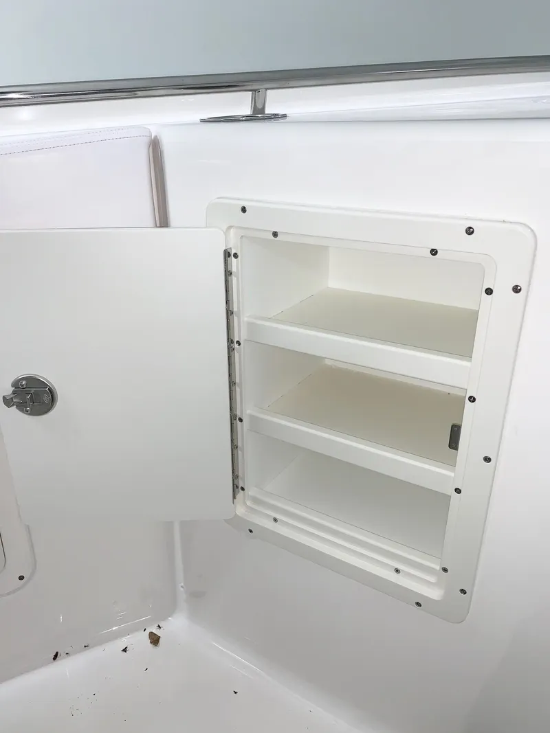 Slide: The Image of 2024 Robalo 302 boat storage compartment with open door and shelves. - 16