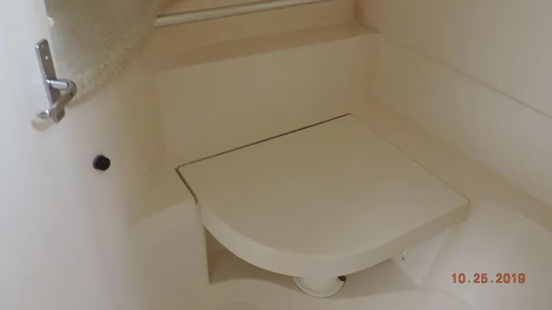 Slide: The Image of 1998 Mainship 30 PILOT boat interior with a compact, foldable seat in a beige finish. - 14