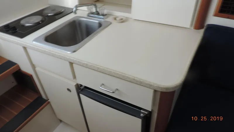 Slide: The Image of 1998 Mainship 30 PILOT boat kitchen with sink, stove, and compact fridge. - 16