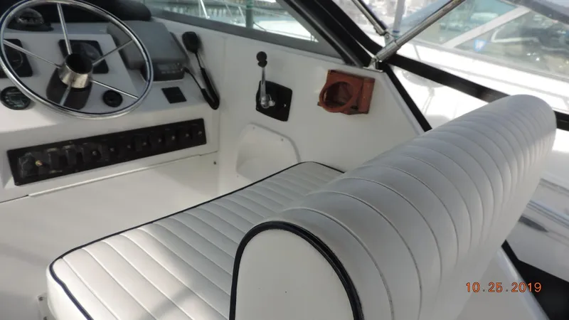 Slide: The Image of 1998 Mainship 30 PILOT helm with white cushioned seating and control panel. - 8